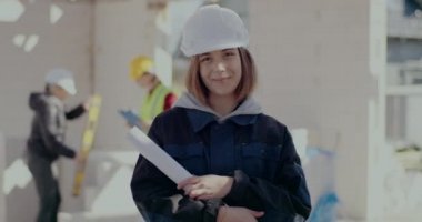 Gülümseyen kadın mimar elinde bir plan tutuyor.