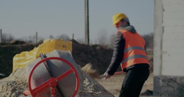 Mannelijke werknemer zet cement in mixer op bouwplaats — Stockvideo