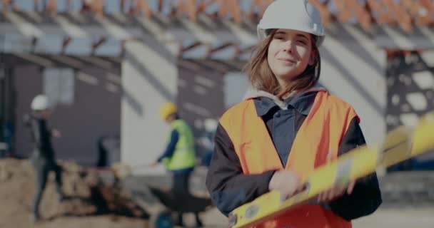 Supervisor feminino confiante carregando ferramenta de nível no ombro — Vídeo de Stock