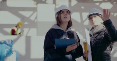 Genç bayan mimar mühendise anlatırken el kol hareketi yapıyor.