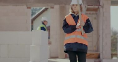 Beton duvarı düzeyi ile inceleyen kadın inşaat işçisi