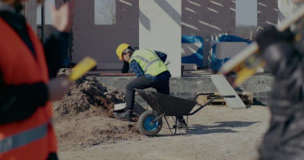 Férfi munkás gyűjtése homok talicska lapáttal — Stock videók