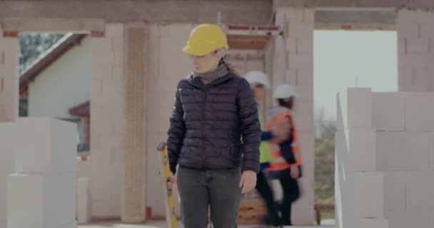 Female supervisor examining concrete wall with level — Vídeo de stock