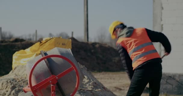 Mannelijke bouwvakker zet cement in mixer — Stockvideo