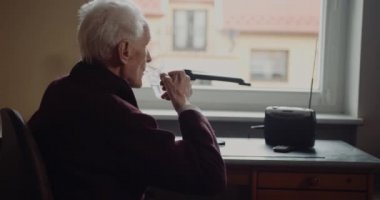Yaşlı, yaşlı, yaşlı, yaşlı adam evde tek başına su içiyor.