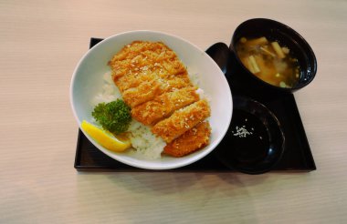 Japon Katsudon veya bol yağda kızartılmış domuz eti kasede miso çorbası ile kahverengi bir tabakta.