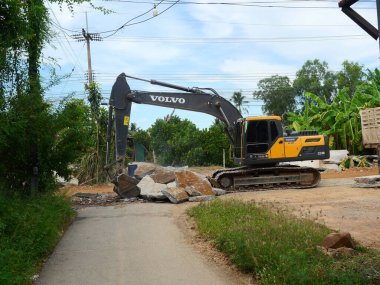 Prahuap Khiri Khan, Tayland - 15 Haziran 2022: Güç kürek kovası ile kepçe kazısı kazıcı ve ağır makineler tarafından yoldaki beton levha üzerinde büyük bir ısırık aldı