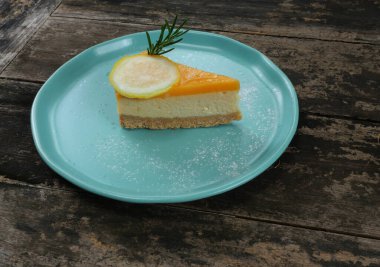 Lemon fruit slice on Cheesecake pie on blue color plate, Sweet food with brown table in background