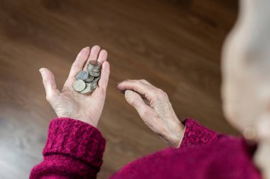 10 rublelik madeni paralar bir emeklinin ellerine dökülüyor, yoksulluk kavramı.