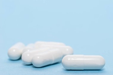 Mavi masaya saçılmış beyaz haplar. Reklam, web geçmişi ya da diğer fikirler için özel teklifler alın. Tıbbi, eczane ve sağlık hizmetleri konsepti. Uzayı kopyala Metin veya logo için boş yer.