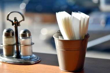 Peçeteler ve tuzluk bulanık arkaplanda Bokeh ile masanın üzerinde.