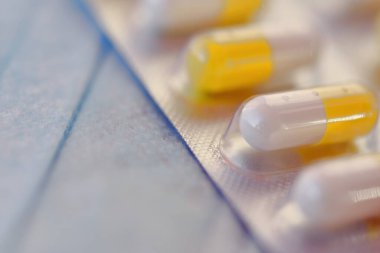 Tıbbi bir maskenin arka planında kapsüllerdeki beyaz-sarı haplar. bulanık
