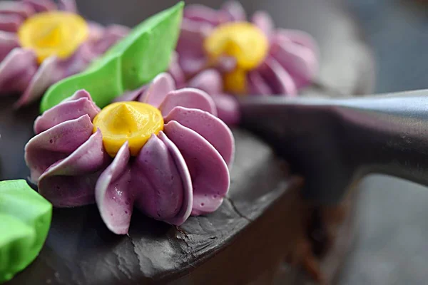 Нож разрезает шоколадный торт сливочными цветами — стоковое фото