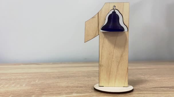 Una campana balanceándose sobre un número uno de madera. vídeo — Vídeo de stock
