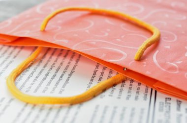 Eski bir gazetenin arka planında parlak turuncu bir çanta.. 