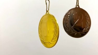 Gri arkaplanda beyaz-mavi-kırmızı kurdeleyle birinci ve ikinci olmak üzere iki madalya.