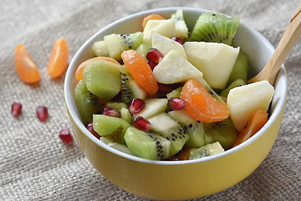 fruit salad of tangerines kiwi apples pomegranate seeds.