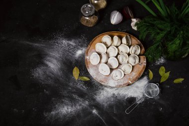 Traditional Russian food dumplings on a cutting board, ravioli, pelmeni, dark background, copy space