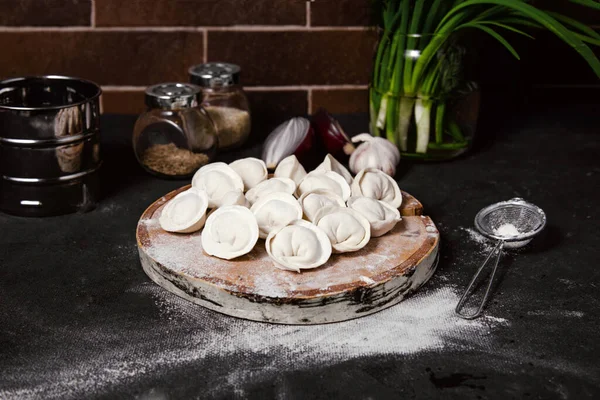 Geleneksel Rus hamur köfteleri kesim tahtasında, ravioli, pelmeni, koyu arka plan; 