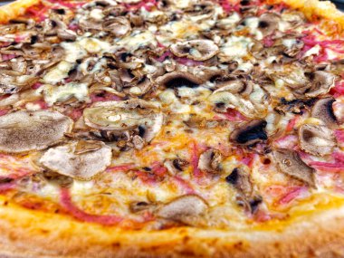 Tahta masada servis edilen peynirli ve mantarlı İtalyan pizzasını kapat.