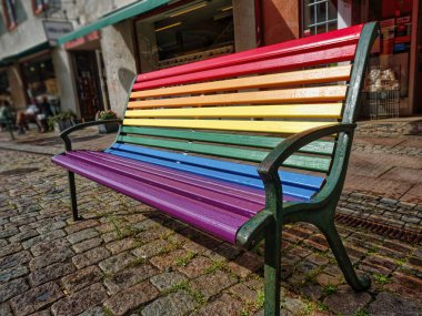 Gökkuşağı renkli bank. Gurur Günü konsepti. Sokakta gökkuşağı renkleriyle boyanmış bir banktan ahşap.