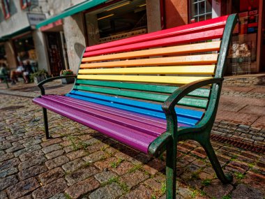 Gökkuşağı renkli bank. Gurur Günü konsepti. Sokakta gökkuşağı renkleriyle boyanmış bir banktan ahşap.