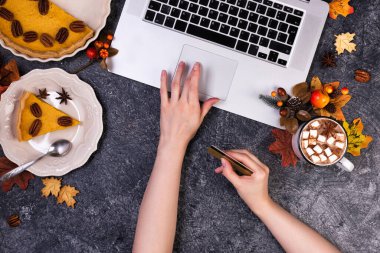 Çalışma alanı dizüstü bilgisayar, sıcak çikolata ve ev yapımı balkabağı turtası.