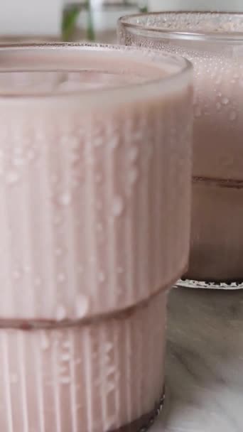 冰镇巧克力奶昔在一个流行的波纹玻璃杯大理石盘 可可牛奶在木桌上喝 垂直录像 — 图库视频影像