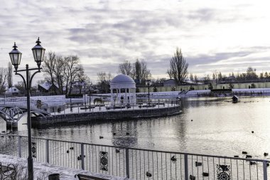 Ördeklerin, kazların ve kuğuların yaşadığı yapay göleti olan karla kaplı bir şehir parkı.