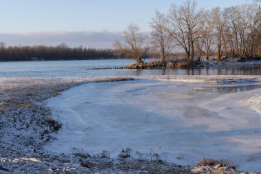 Karla kaplı bir nehir kenarında buzlar.