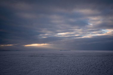 Güneş ışınları gün batımında bulutları delip geçer ve Pivikha Dağı yakınlarındaki buzla kaplı nehir Dinyeper 'ine düşer.
