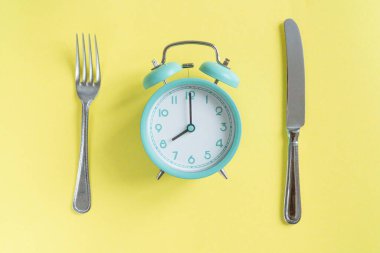 intermittent fasting concept - blue alarm clock, top view