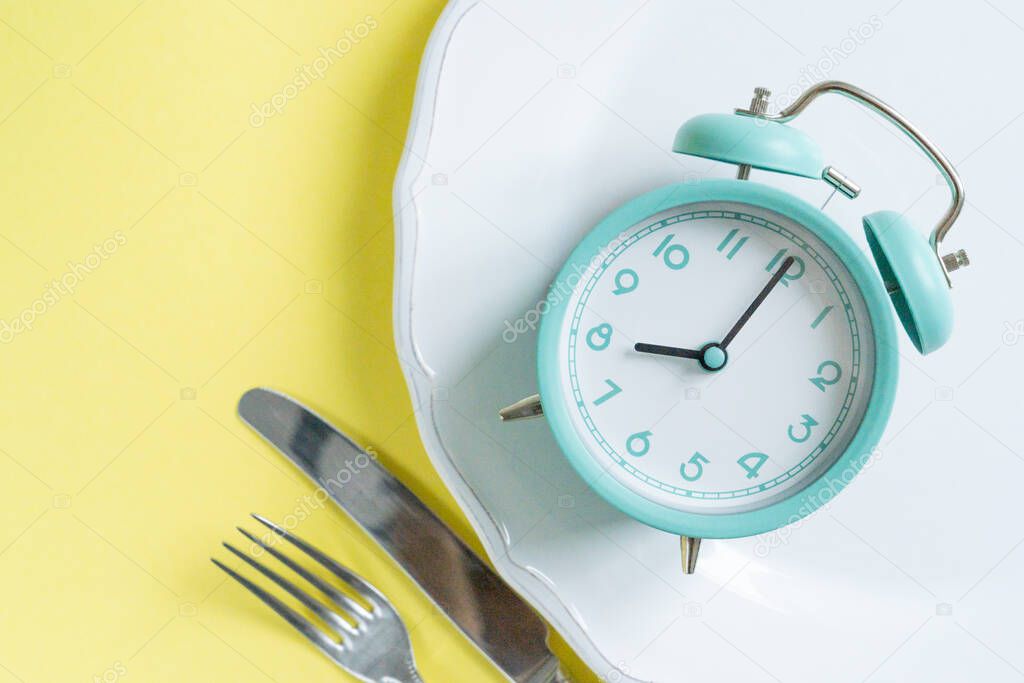intermittent fasting concept - blue alarm clock, top view