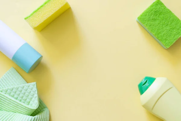 Cleaning concept - cleaning supplies on pastel yellow background, top view
