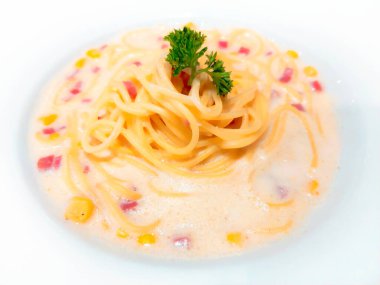 Carbonara Carbonara spagettisi, geleneksel İtalyan yemeği ve tatlı bir tadı var. Lezzetli. Jambon ve mısır kreması sosuyla kaplanmış, maydanoz yapraklarıyla süslenmiş ve beyaz bir tabakta servis edilmiş..