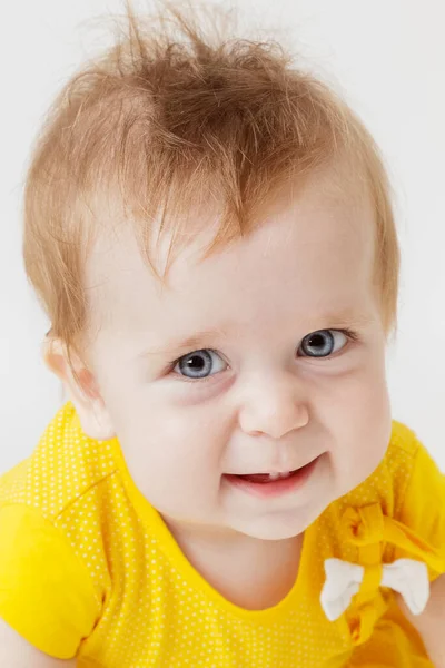 Sarı elbiseli küçük kız gülümsüyor.