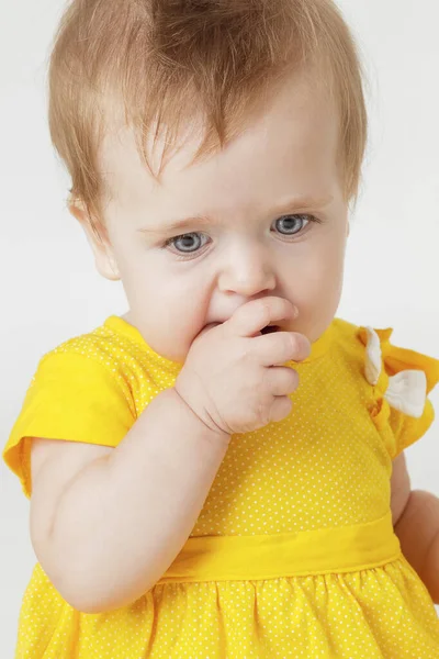 Little girl in the yellow dress on a light background — Stock Photo, Image