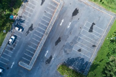 Araba parkının aşağısındaki hava manzaralı caddede beyaz çizgili trafik levhası var. Araba manzarasının üstünde park yerinde sıra halinde araba park alanının dışında..