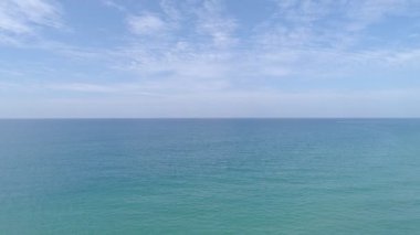 Turkuaz okyanus suyuyla tropik deniz ve kumlu sahile çarpan dalgalar. Gökyüzü manzaralı deniz cenneti adası.