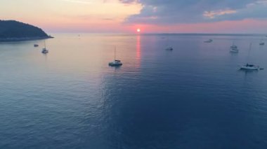 Yelkenli teknelerle deniz yüzeyinin üstünde renkli günbatımı. Phuket Denizi üzerinde uçan insansız hava aracı. Güneş ışığını bir su yüzeyinde yansıttı.