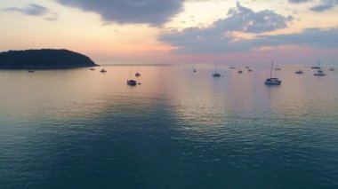 Yelkenli teknelerle deniz yüzeyinin üstünde renkli günbatımı. Phuket Denizi üzerinde uçan insansız hava aracı. Güneş ışığını bir su yüzeyinde yansıttı.