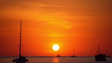 Tropikal denizde güzel bir günbatımında yelkenli ya da su yüzeyinde yansıyan güneşle gündoğumu göğünde yelken aç. Phuket Adası 'nda okyanus üzerinde gün batımı Tayland' da inanılmaz deniz akşamı karanlık gökyüzü