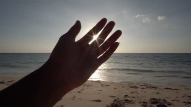 İnsanın eli güneş ve gün batımını aydınlatmaya çalışıyor. Deniz üzerinde gökyüzü kavramsal sahne. Tanrı 'ya olan inanç bir din kavramı.