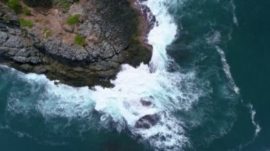 Mavi bir okyanustaki deniz kıyısı kayalarının tepesindeki drone kamerası Turkuaz deniz yüzeyindeki inanılmaz deniz dalgaları kayalara çarpıyor. Hava aracı 4K 'lık okyanus manzaralı, kaya kayalıkları olan 4K' lık yüksek kalite.