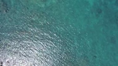 Mavi bir okyanustaki deniz kıyısı kayalarının tepesindeki drone kamerası Turkuaz deniz yüzeyindeki inanılmaz deniz dalgaları kayalara çarpıyor. Hava aracı 4K 'lık okyanus manzaralı, kaya kayalıkları olan 4K' lık yüksek kalite.