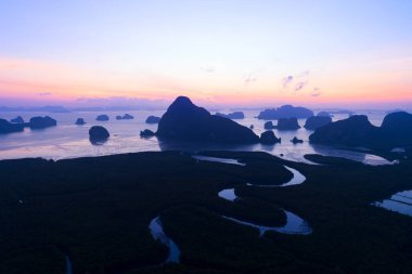 Sabahın ilk ışıklarıyla deniz ve mangrov ormanlarının üzerinden doğan güzel gökyüzünün insansız hava görüntüsü.