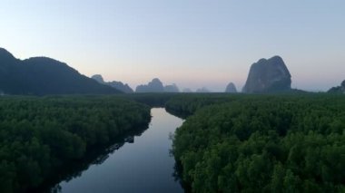 Sabahın ilk ışıklarıyla deniz ve mangrov ormanlarının üzerinden doğan güzel gökyüzünün insansız hava görüntüsü.
