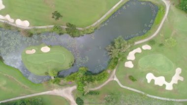 Golf sahasının havadan görünüşü yeşil çimenleri ve ağaçları golf sahasına koyuyor ve yeşil üst manzarayı yaz güneşli günlerinde golf sahalarının üzerine koyuyor.