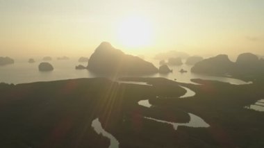 Sabahın ilk ışıklarıyla deniz ve mangrov ormanlarının üzerinden doğan güzel gökyüzünün insansız hava görüntüsü.