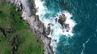 Okyanustaki deniz kıyısı kayalarının insansız hava aracı kamerası. Güzel deniz yüzeyi. Tayland 'ın Phuket adasında kayalıklara çarpan inanılmaz deniz dalgaları. Hava gözlem dronu 4k Yüksek kalite görüntü